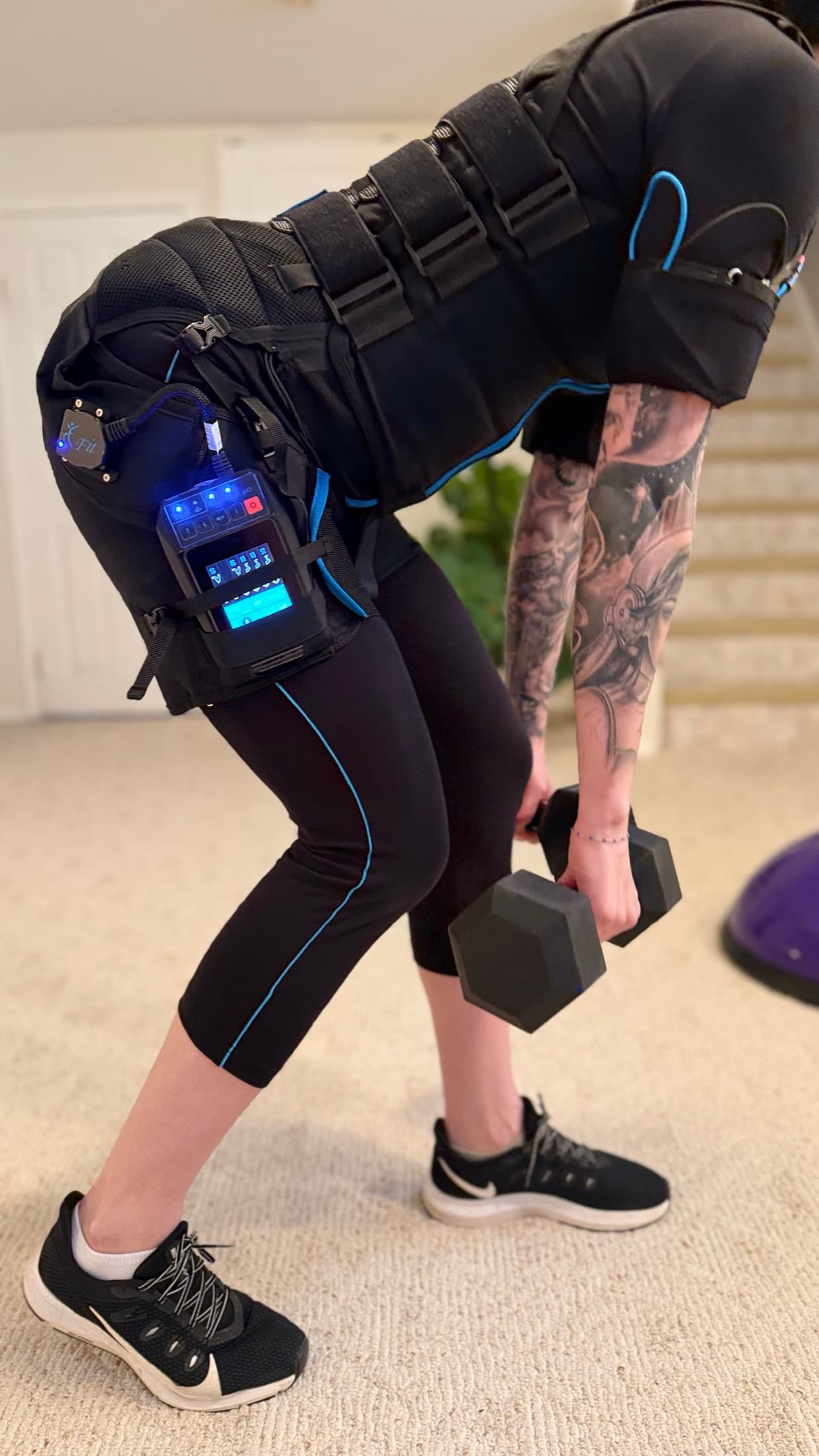 Client wearing an EMS training suit while performing a dumbbell movement.